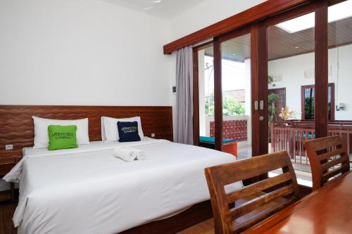 a bedroom with a large white bed with green and blue pillows at Urbanview Hotel Arta Guna Casa in Kerobokan