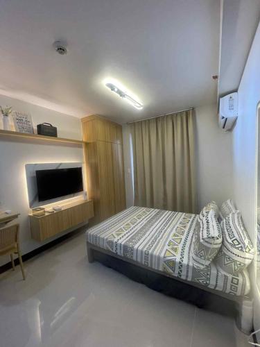 a bedroom with a bed and a television in it at Affordable Condo Unit in Saekyung Phase 3 in Suba