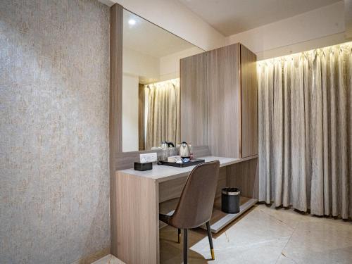 a room with a desk with a chair and a mirror at Hotel Spencer-Navi Mumbai in Navi Mumbai