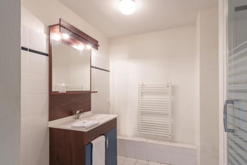 a white bathroom with a sink and a mirror at Appart'City Classic Antibes in Antibes