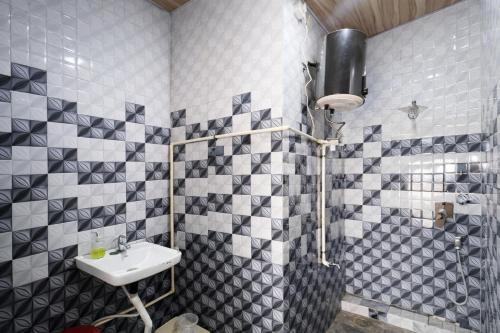 a bathroom with black and white tiled walls and a sink at The Golden Wings Hotel in Dewās
