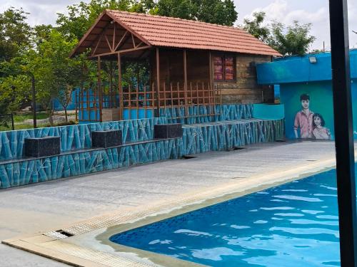 a building next to a swimming pool with a painting of a man at Vara Farm in Kanakapura