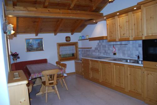 a kitchen with wooden cabinets and a table and a sink at Bait da Befin in Livigno