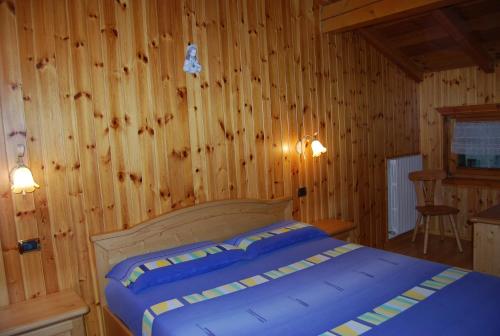 una camera con un letto in una stanza con pareti in legno di Bait da Befin a Livigno