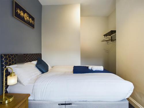 a bedroom with a large white bed with blue pillows at Pottery House - Stoke on Trent -Free parking- Central Location - Sleep 8 in Stoke on Trent