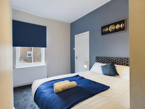 a bedroom with a bed with blue walls and a window at Pottery House - Stoke on Trent -Free parking- Central Location - Sleep 8 in Stoke on Trent