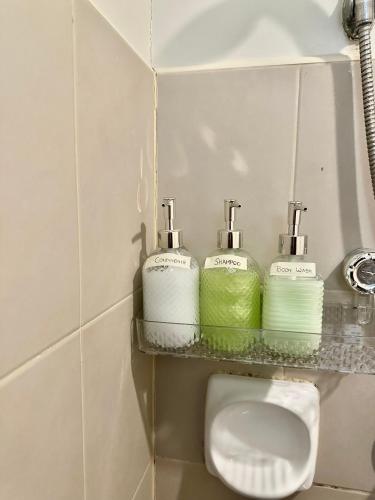 a bathroom with three soap dispensers on a shelf above a toilet at Modern Studio IT Park Fast Wi-Fi, Pool,Netflix in Sampong