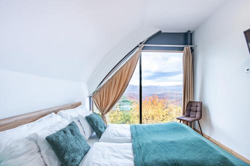 a bedroom with a bed and a large window at Üveghuta Vendégház in Vágáshuta