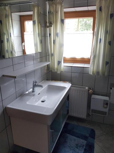 een badkamer met een wastafel, een spiegel en een raam bij Haus Deutinger in Piesendorf