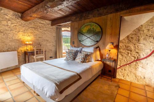 a bedroom with a bed and a stone wall at La Tour d'Enguerne in Montmeyan