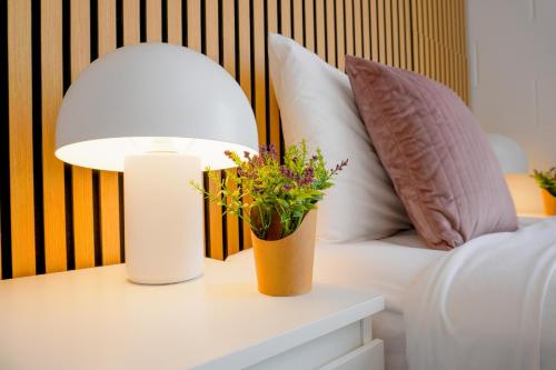 a lamp on a table next to a bed with pillows at Train, Zoo & Eden Park Nearby - Arcade, Disney Plus- Free Parkings- Central & Peaceful in Auckland