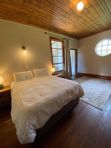 a bedroom with a large white bed with a wooden ceiling at Stoneygate Farm in Wakkerstroom