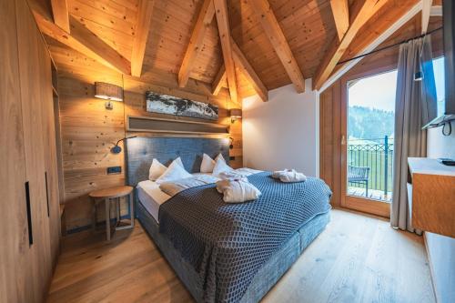 a bedroom with a bed in a room with wooden ceilings at Hotel Babymio in Kirchdorf in Tirol