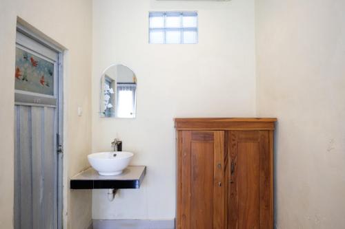 a bathroom with a sink and a wooden cabinet at Lilis Cempaka Mas Guesthouse in Canggu