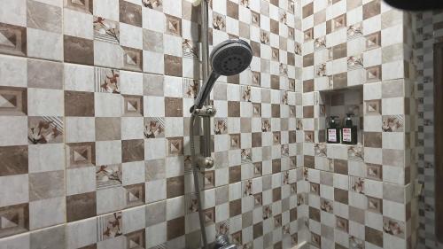 a shower in a bathroom with a tiled wall at ADA WAKTU Bed & Breakfast in Yogyakarta