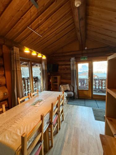 Chalet Le Ranch في لي دوز آلب: طاولة خشبية كبيرة في غرفة بها نوافذ