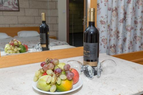 a plate of fruit on a table with two bottles of wine at Hotel & Museum Dona Gracia in Tiberias