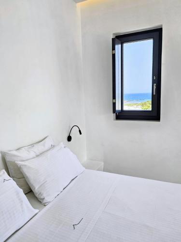 a bedroom with a white bed and a window at myLithos Suites in Monolithos