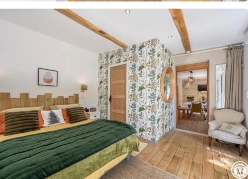 a bedroom with a large green bed and a chair at L Orée du Bois in Agnetz