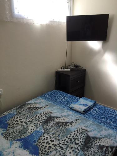 a bedroom with a bed with a blue comforter and a television at Guest house Ashdod-beach in Ashdod