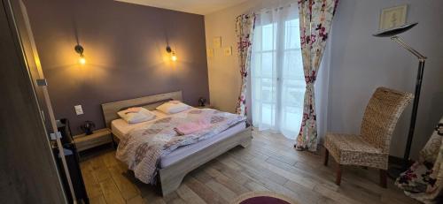a bedroom with a bed and a window and a chair at LA MAISON DU MUGUET - Accueil Chevaux - Horse Friendly in Liart