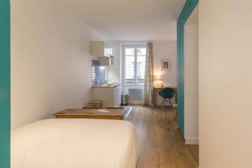 Un dormitorio con una cama y un escritorio. en Les Toits de Paris, en París