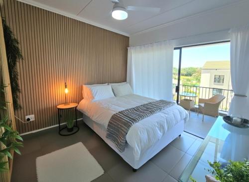 a bedroom with a bed and a balcony at Luxury Spa unit, Private Sauna, Central Ballito in Ballito