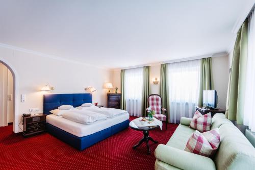 a hotel room with a large bed and a couch at Hotel Hirlanda in Zürs am Arlberg