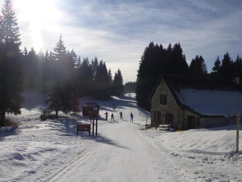 a group of people skiing in the snow next to a building at Hôtel Au Feu De Bois in Autrans