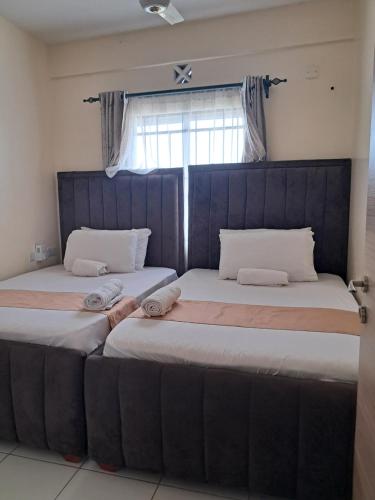 two beds sitting next to each other in a bedroom at Cozy 2 BR with 3 Beds, AC & Hot Shower at Buxton Point Apartments Off RG Road Gate A in Mombasa