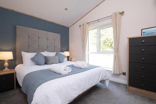 a bedroom with a large bed with two towels on it at Willow lodge in Brynteg