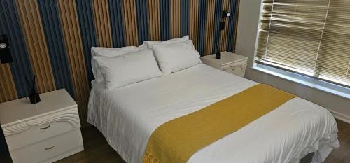 a bedroom with a bed with white sheets and pillows at The White House at Plattekloof in Plattekloof