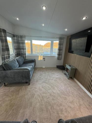 a living room with a couch and a tv at Bethany Woodland Lodge in Winchburgh