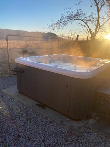 a bath tub sitting on the ground with the sunset at Bethany Woodland Lodge in Winchburgh