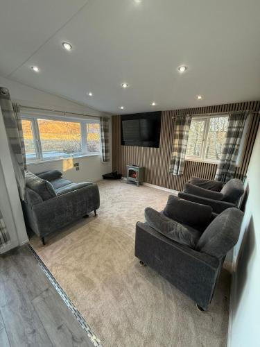 a living room with couches and a flat screen tv at Bethany Woodland Lodge in Winchburgh