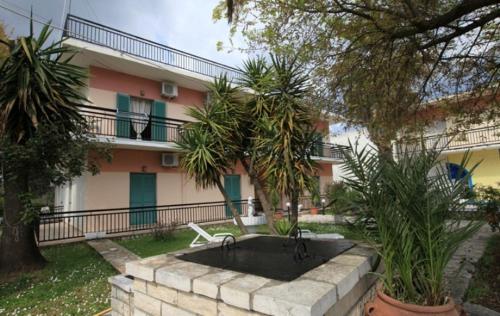 a fountain in front of a house with trees at Maritsas Apartments in Roda
