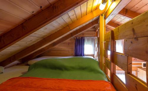 an attic bedroom with a green bed in a wooden cabin at Apartments Brunarica in Moravske Toplice