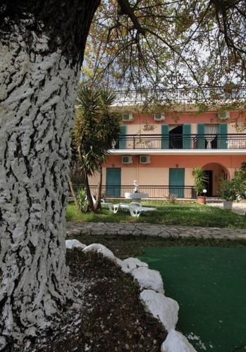 a building with a tree in front of a body of water at Maritsas Apartments in Roda