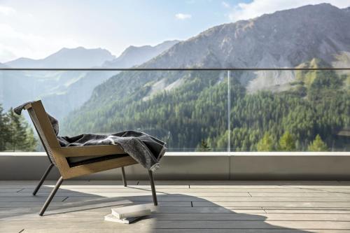 a chair on a balcony with a view of a mountain at Tschuggen Grand Hotel - The Leading Hotels of the World in Arosa