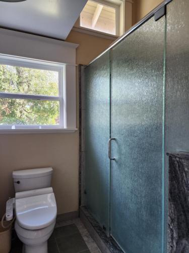 a bathroom with a toilet and a glass shower stall at Amitabha Wine Country Cottage in Santa Rosa