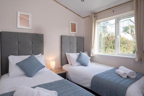 two beds in a room with two windows at Olive Lodge Benllech in Brynteg