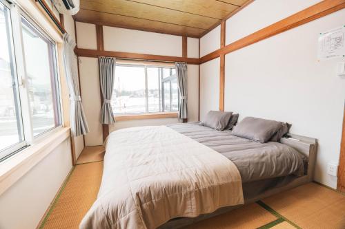 a bedroom with a large bed in a room with windows at Myoko Yuki House in Myoko