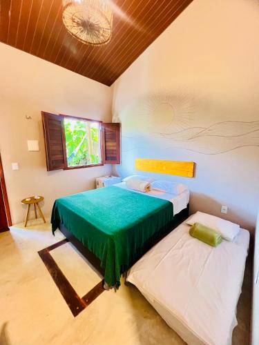 a bedroom with two beds with green sheets and a window at Recanto do cajueiro in Flecheiras