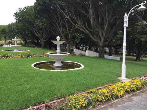 a fountain in the middle of a park with flowers at Anoud Manor in Hout Bay