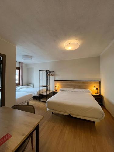 a bedroom with a large white bed and a table at Hotel NIU a 50 m del Funicamp in Encamp