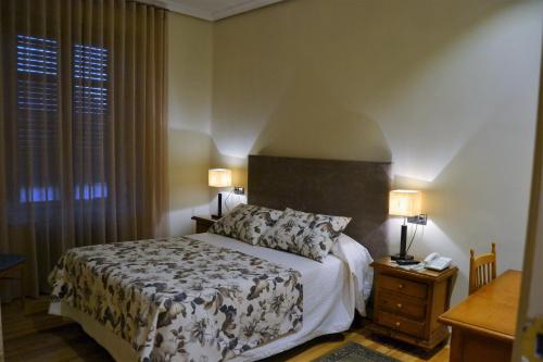 a bedroom with a bed and two lamps and a table at Hotel Villegas in Valencia de Don Juan