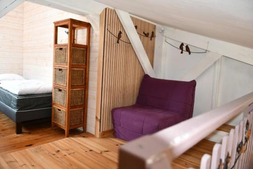a attic room with a purple chair and a bed at Gîte Le Cincle au cœur du massif des Vosges in La Bresse