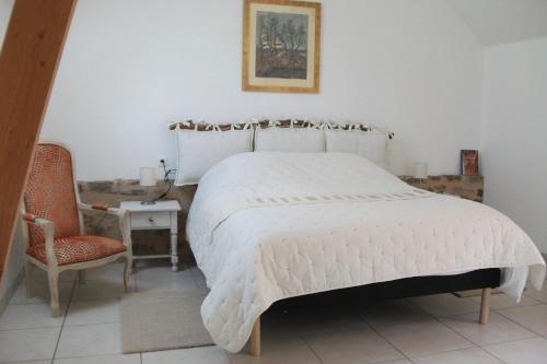 a bedroom with a large white bed and a chair at Gîte Les Noyers in Noailhac
