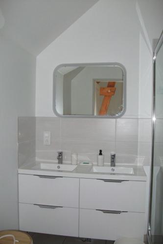 a white bathroom with a sink and a mirror at Gîte Les Noyers in Noailhac