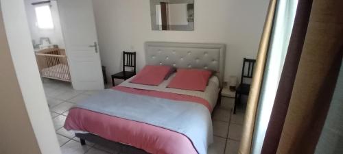 a bedroom with a bed with two pink pillows at Au pays du Ventoux in Le Thor